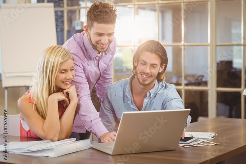 Smiling businessman using laptop while colleagues © WavebreakmediaMicro