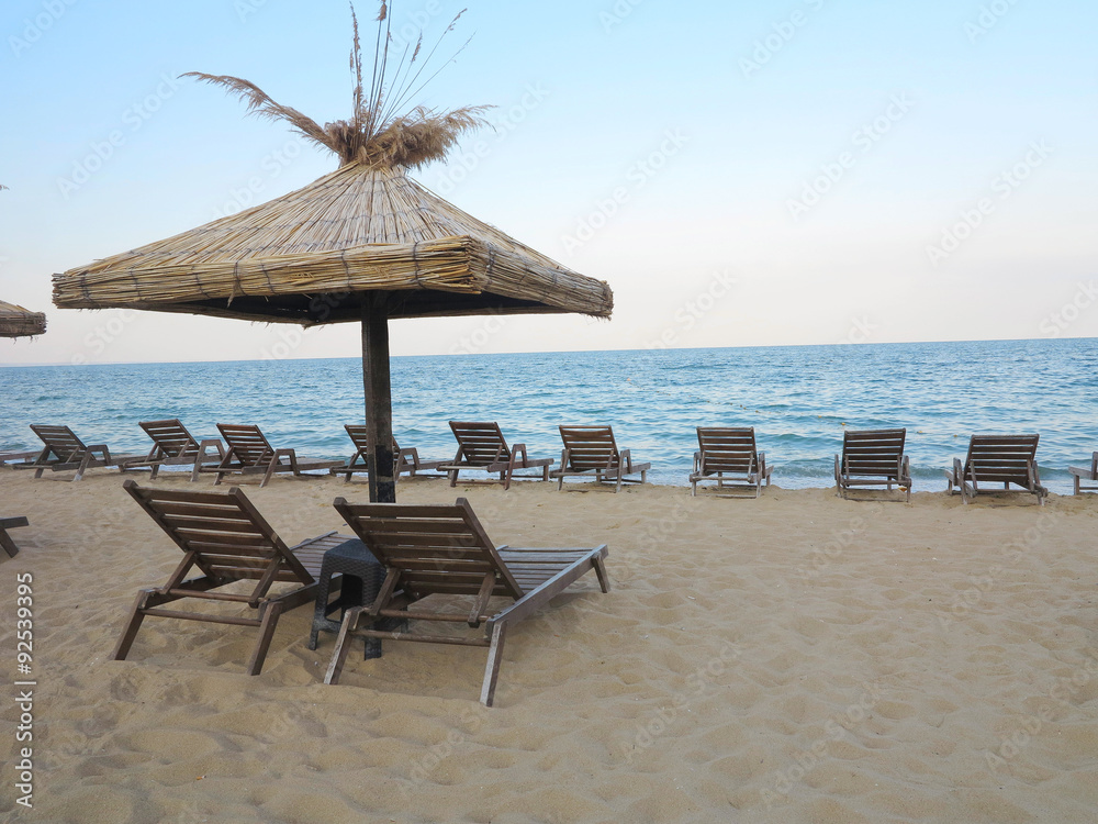 Beach chairs and umbrella on the sand near sea, blue sky