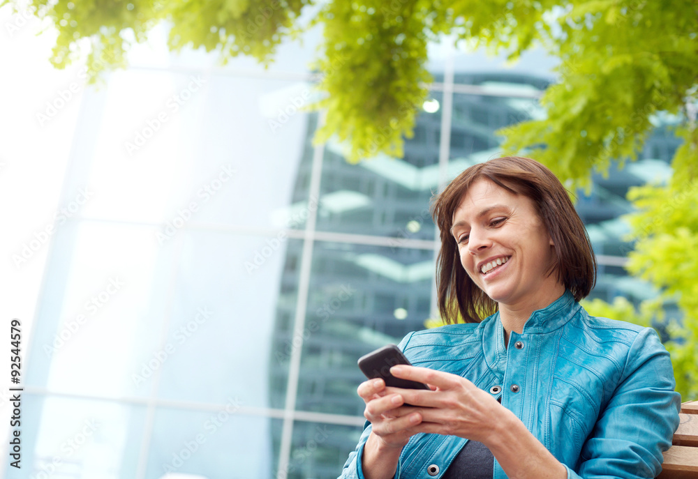 Smiling middle aged woman using mobile phone outside Smiling middle aged woman using mobile phone outside