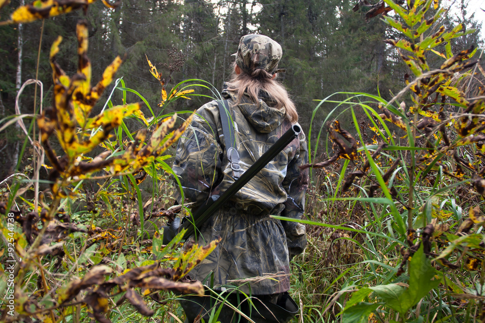 Woman hunter with gun on the riverside