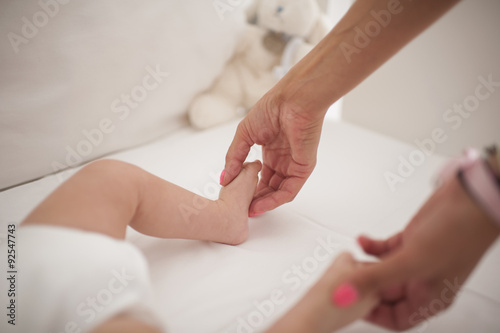 Portrait of a mother playing with the feets of her cute little boy in bed