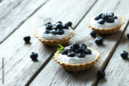 Dessert tartlets with blueberries on grey wooden background