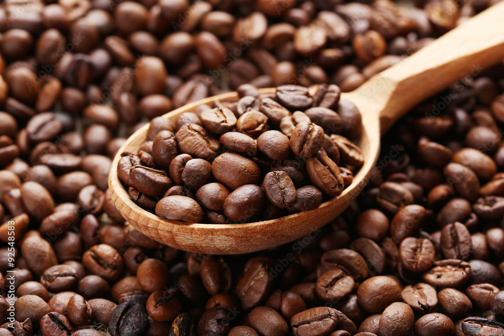 Coffee beans in wooden spoon on the beans background