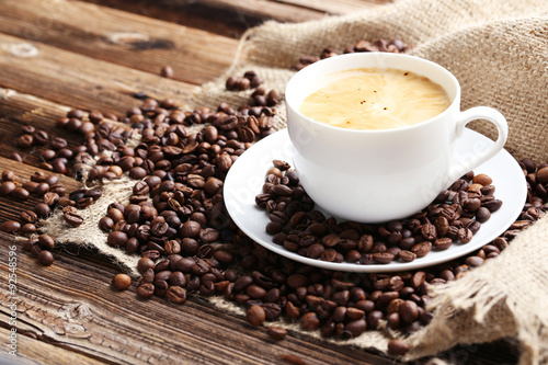 Cup of coffee with coffee beans on a brown wooden background