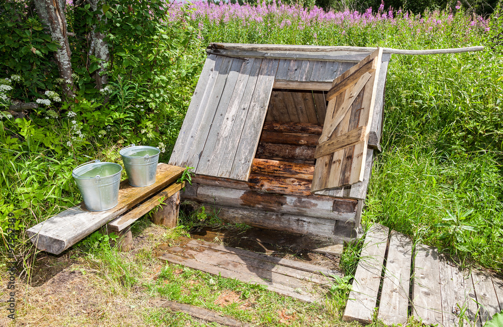 Village wooden water well with the open door and a buckets of wa Village wooden water well with the open door and a buckets of wa