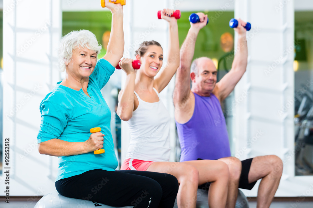 Seniors with trainer in gym at sport lifting barbell Seniors with trainer in gym at sport lifting barbell