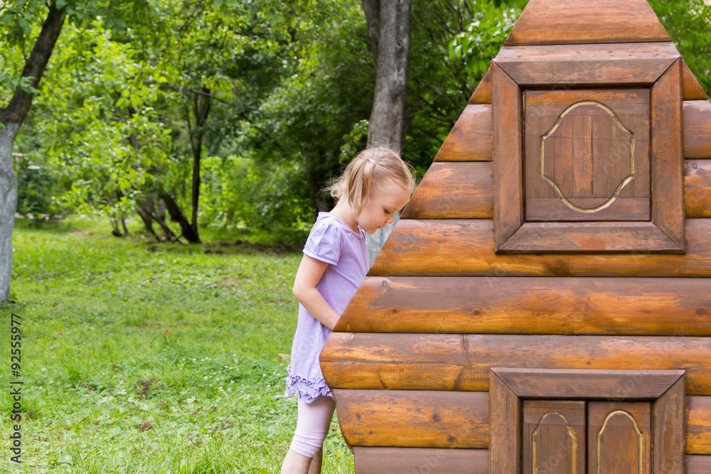 little girl with pigtails playing in toy log cabin
