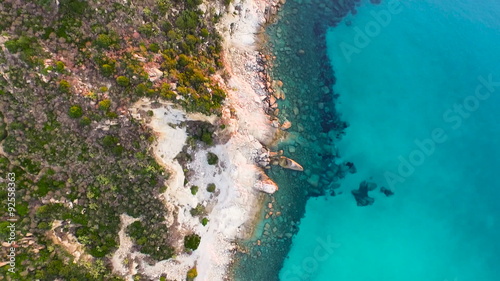 AERIAL: flying over beautiful bay, surrounded by hill with a ruin of watchtower on top
