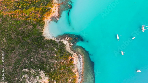 AERIAL: flying over beautiful bay, surrounded by hill with a ruin of watchtower on top

