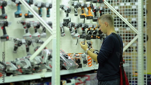Young man choose tools for repair in the store 