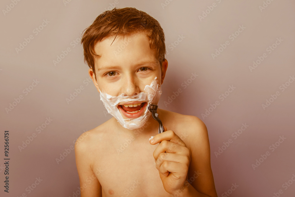 Fototapeta premium Boy teenager European appearance decade shaves face on a gra