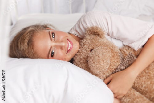 Beautiful happy girl with a teddy bear in the bed