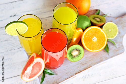 Glasses of different juice with fruits and mint on table close up