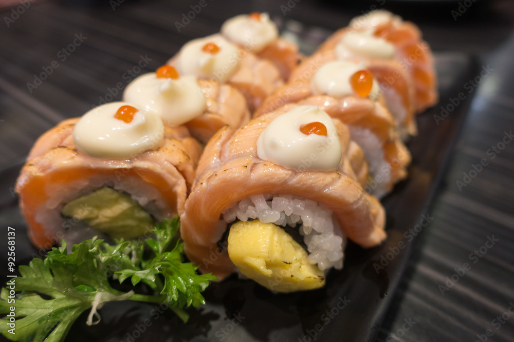 Salmon Sushi Roll with Tamagoyaki on black ceramic plate Salmon Sushi Roll with Tamagoyaki on black ceramic plate