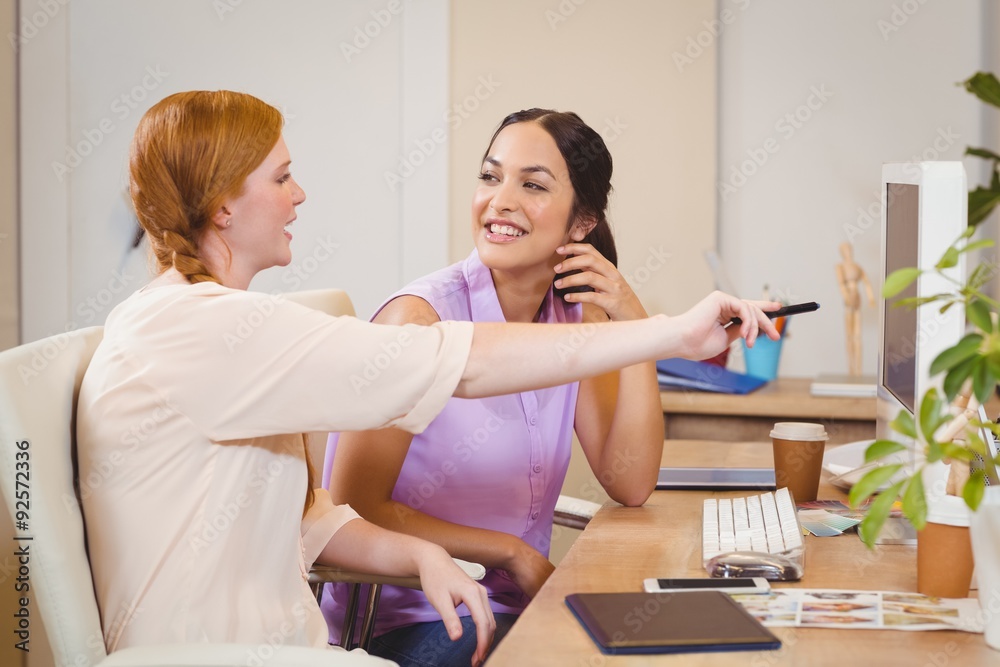 Obraz premium Businesswoman showing something on computer to happy colleague 
