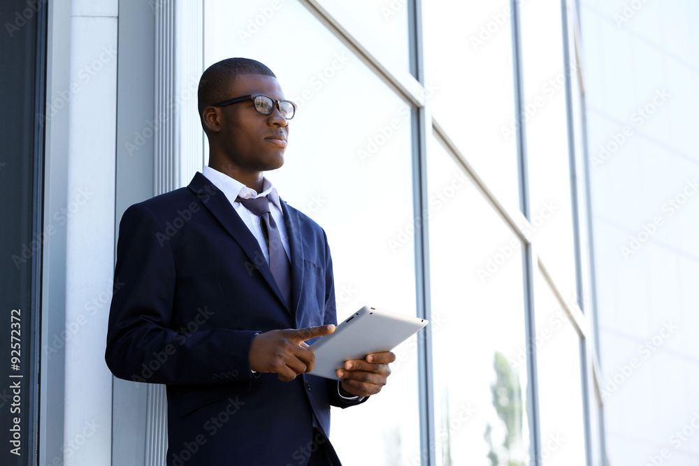 Handsome African American businessman with digital tablet near business centre Handsome African American businessman with digital tablet near business centre