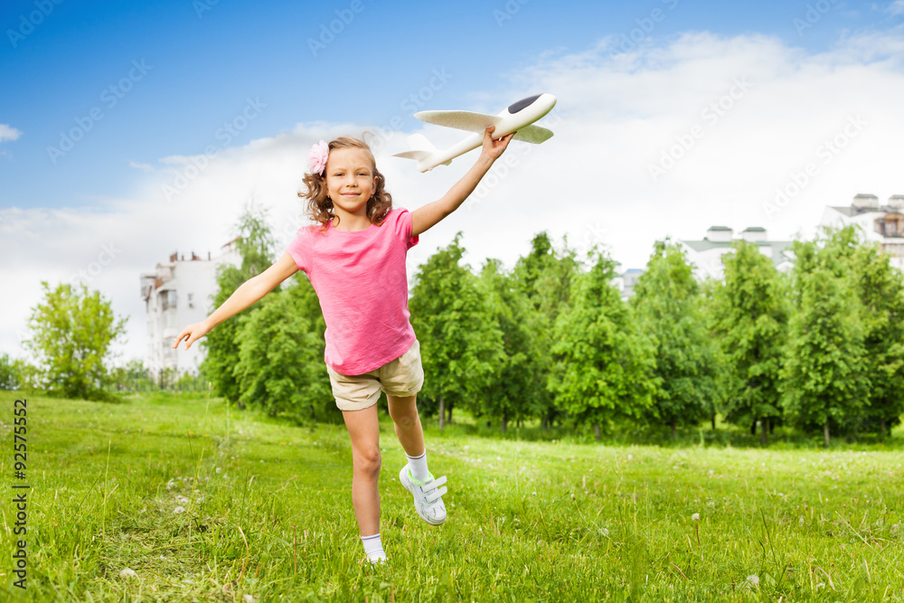 Happy girl holds airplane toy with one leg up Happy girl holds airplane toy with one leg up