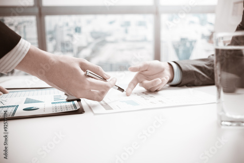 Two businessmen looking at report and having a discussion in off