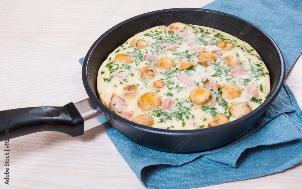 omelet with mushrooms, ham and cheese in a frying pan