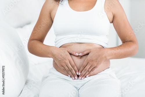 Pregnant woman doing heart sign on her belly