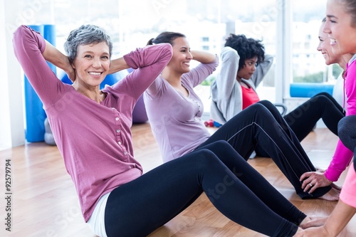 Woman doing sit ups with friends at fitness studio photo