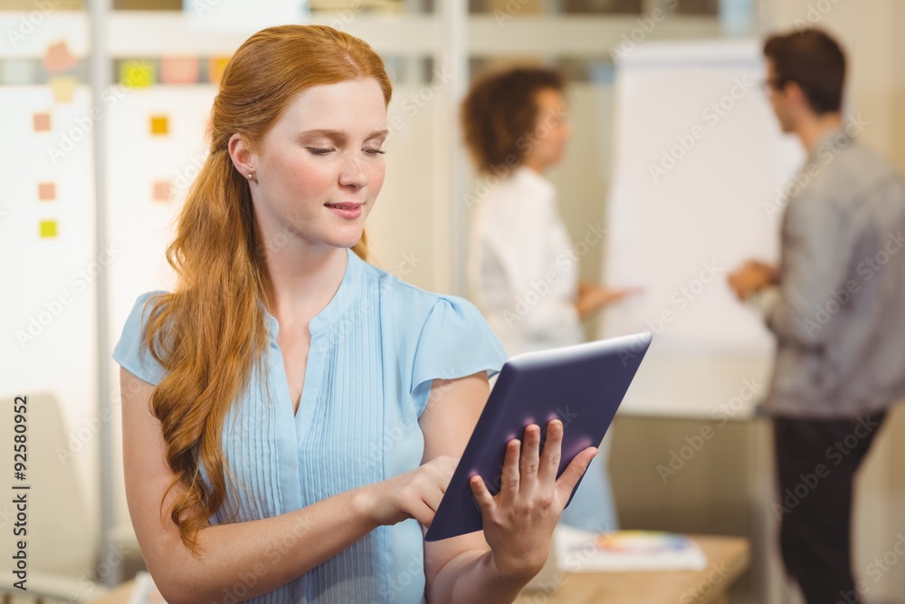 Confident businesswoman using digital tablet with colleagues Confident businesswoman using digital tablet with colleagues