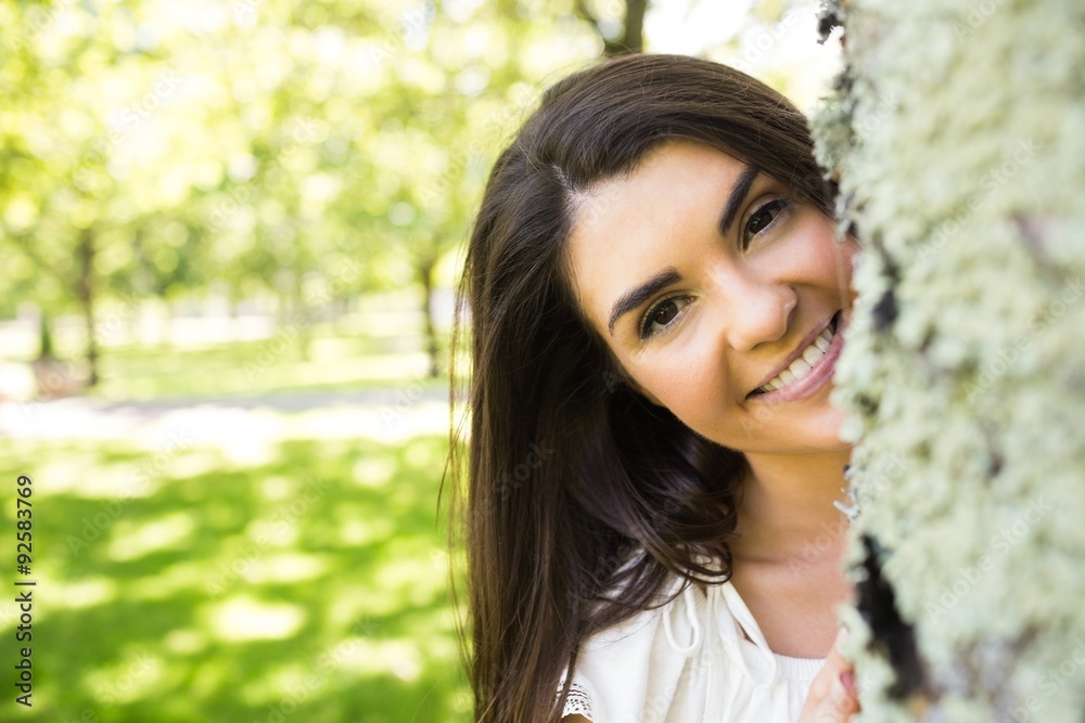 Portrait of smiling woman behind tree trunk Portrait of smiling woman behind tree trunk