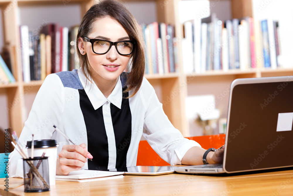 Young woman sitting at the table near her laptop Young woman sitting at the table near her laptop