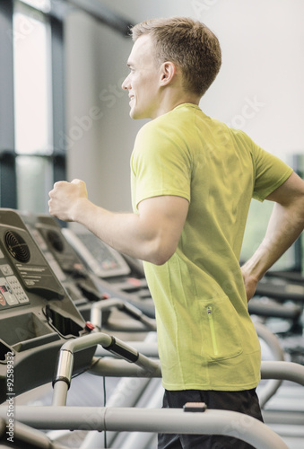 smiling man exercising on treadmill in gym