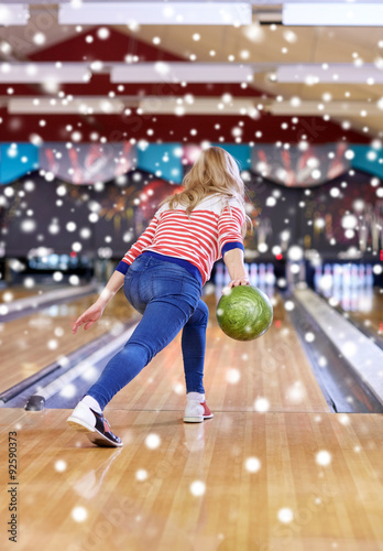 happy young woman throwing ball in bowling club