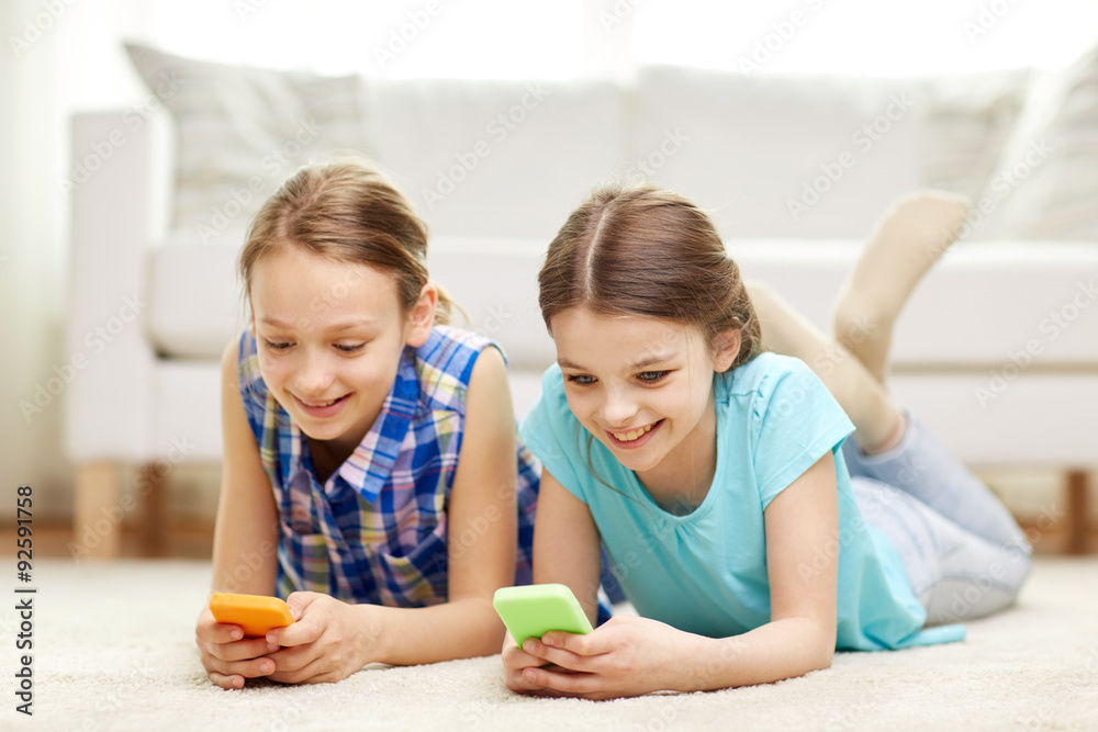happy girls with smartphones lying on floor happy girls with smartphones lying on floor