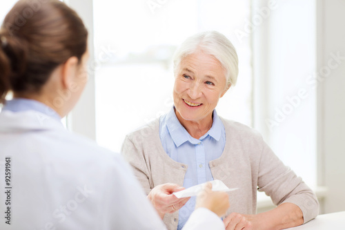 doctor giving prescription to senior woman