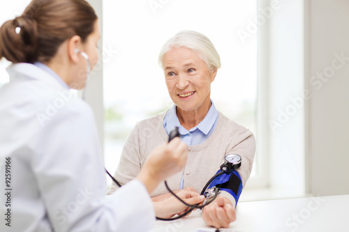 doctor with tonometer and senior woman at hospital photo
