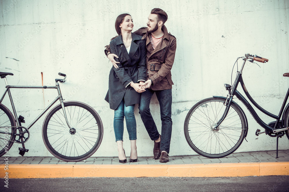 Obraz premium Young couple with a bicycle opposite city 