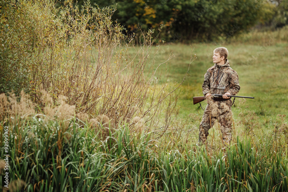 hunter in camouflage clothes ready to hunt with hunting rifle