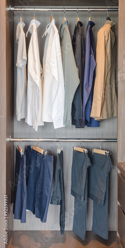 clothes hanging on rail in wooden wardrobe at home