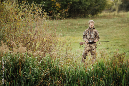 hunter in camouflage clothes ready to hunt with hunting rifle