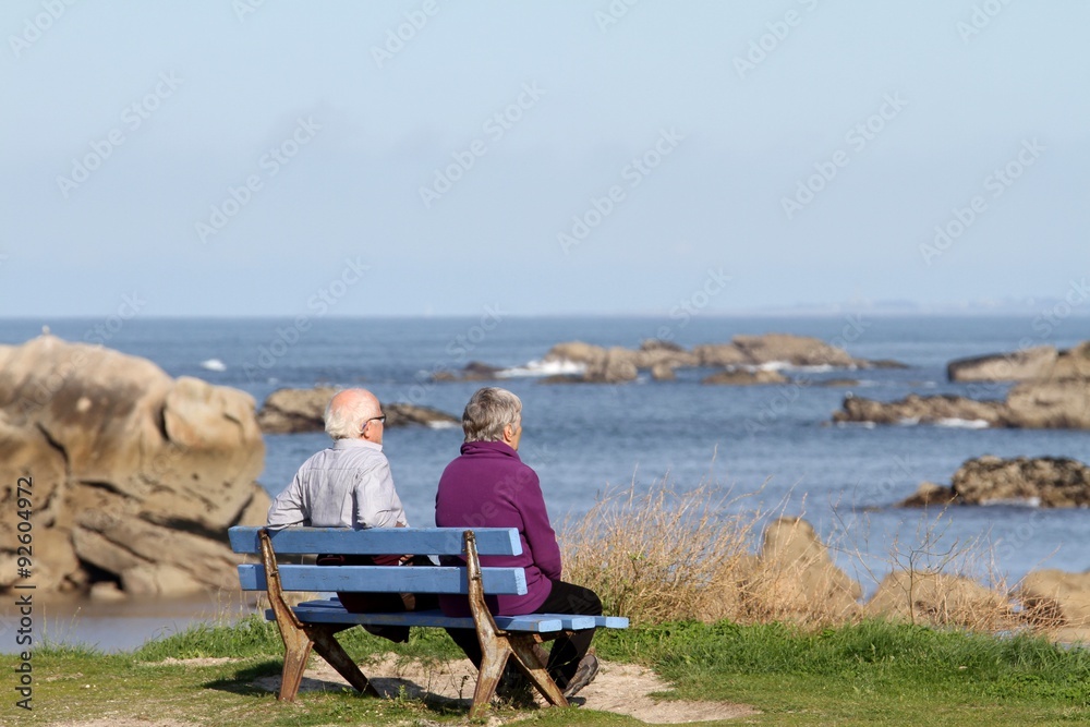 couples de personnes âgées regardant la mer assis sur un banc.
