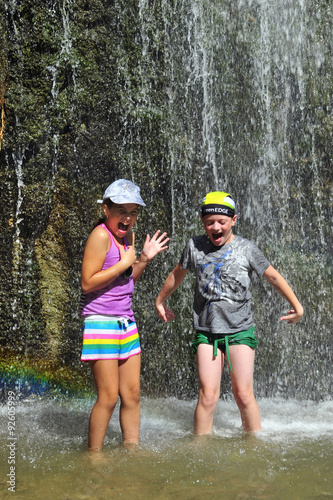 Fototapeta Naklejka Na Ścianę i Meble -  Boy and girl stay under the waterfall stream