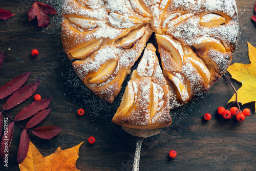 Fotografía Fresh baked apple pie on the wooden table with autumn leaves around