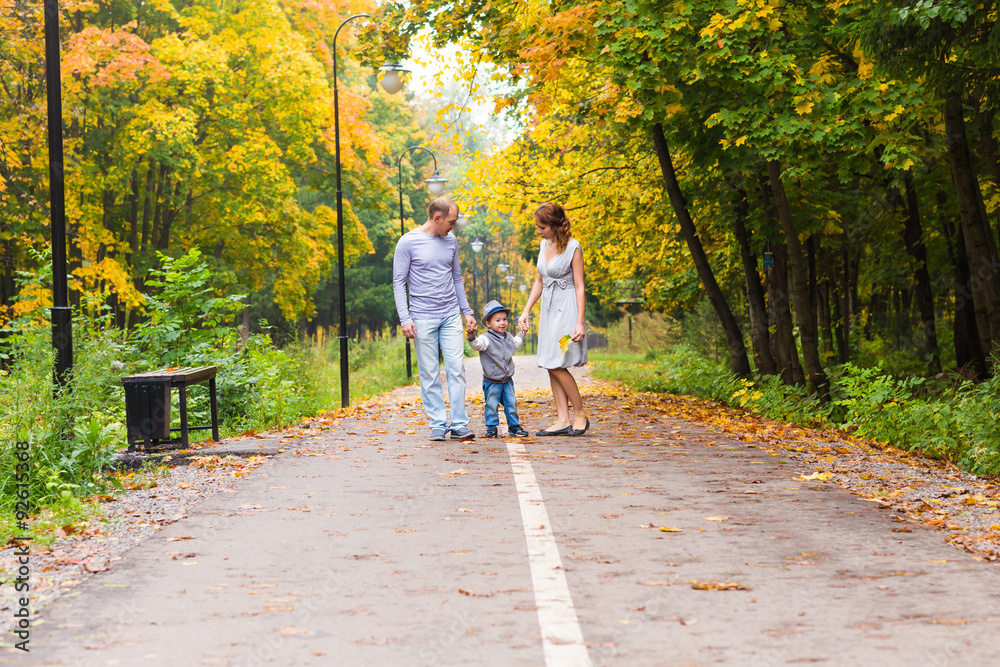 Fototapeta premium Young family for a walk in the autumn park with baby
