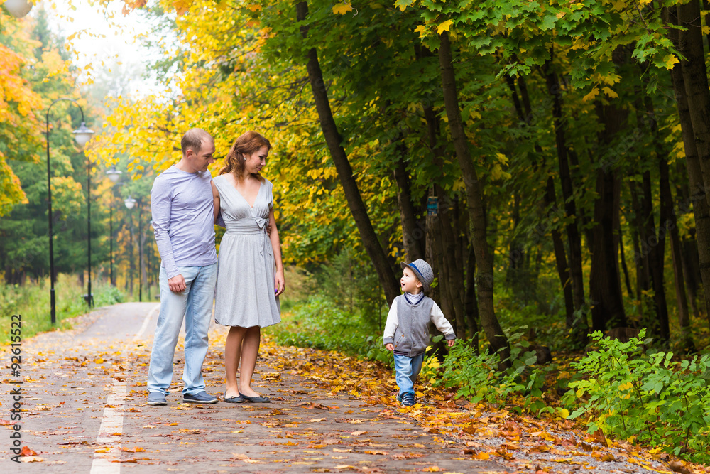 Fototapeta premium Young family for a walk in the autumn park with baby