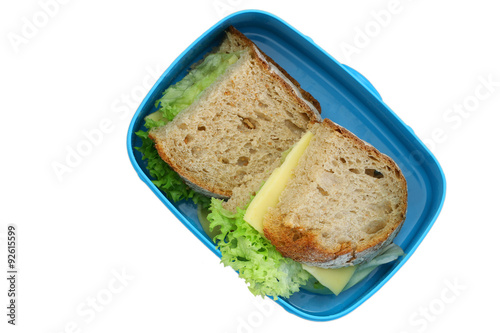 Lunch box containing rustic bread sandwiches with cheese and lettuce isolated on white
