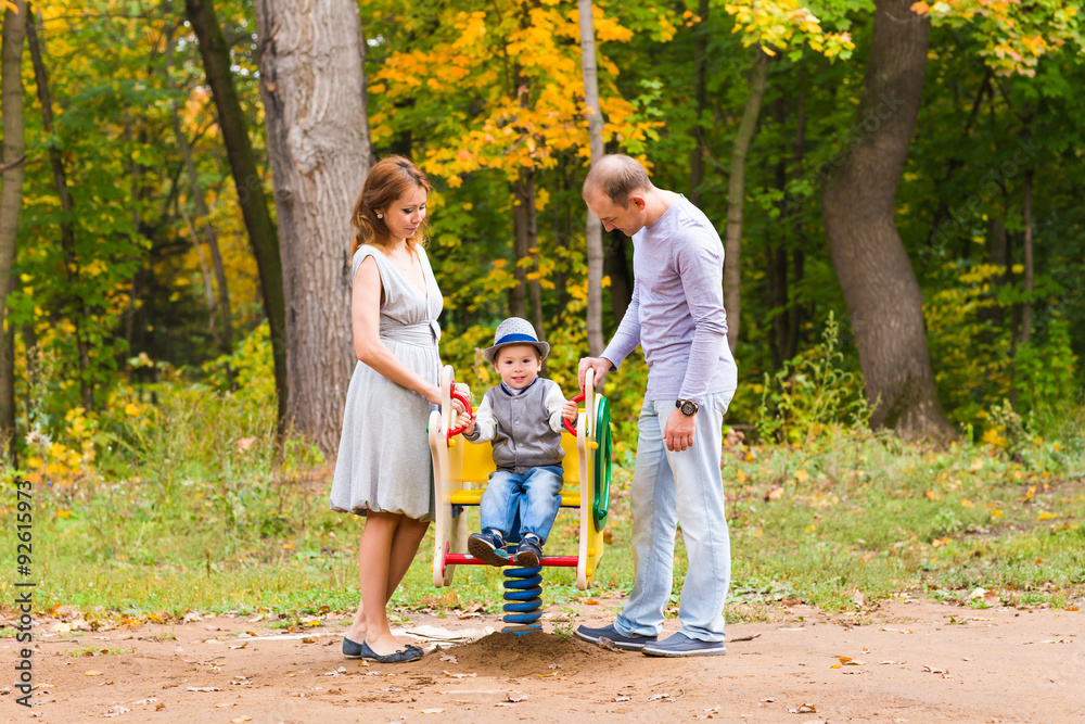 Fototapeta premium Young family for a walk in the autumn park with baby