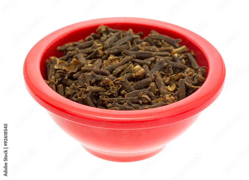 Red dish filled with whole cloves on white background Red dish filled with whole cloves on white background