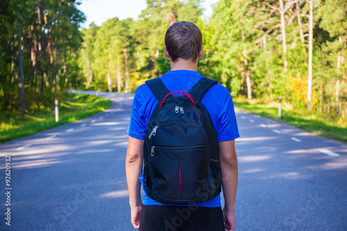 hiking concept - back view of man walking on forest road