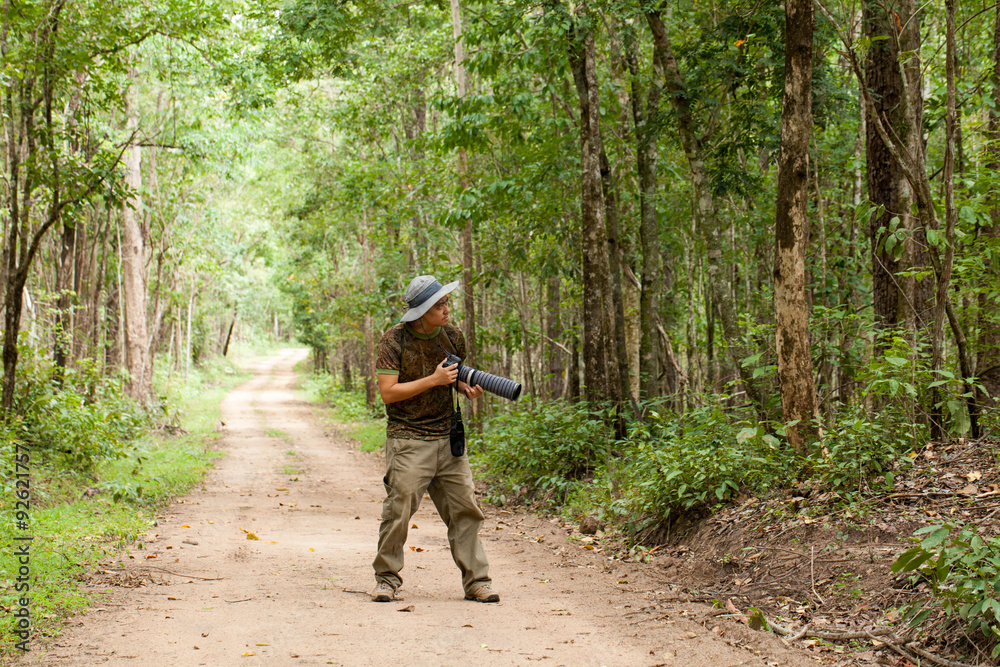 Naklejka premium Adventure photographer, a camouflage adventure guy with camera traveling in the tropical forest,Thailand