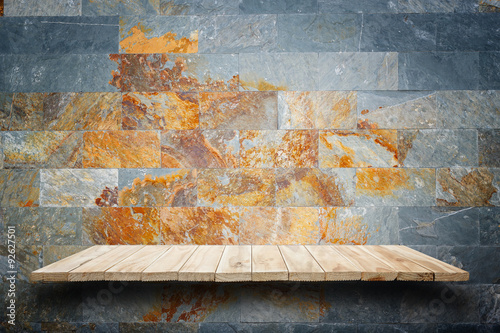 Empty wooden shelves and stone wall background. For product disp photo