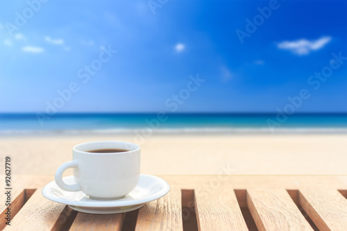 Coffee cup on wood table and view of tropical beach