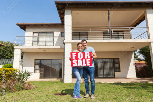 Obraz na plátne couple holding for sale sign in front of house